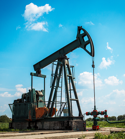 Active oil pump jack operating under a bright blue sky