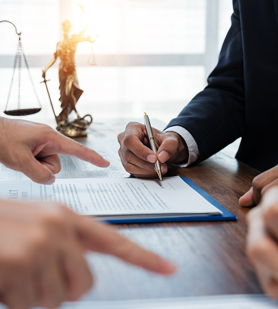 Close-up of a person signing a legal contract near Lady Justice