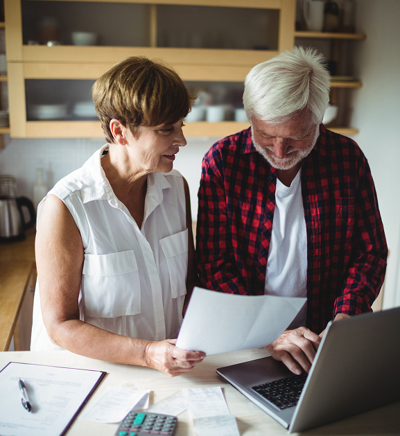 Senior couple reviewing documents and using a laptop at home